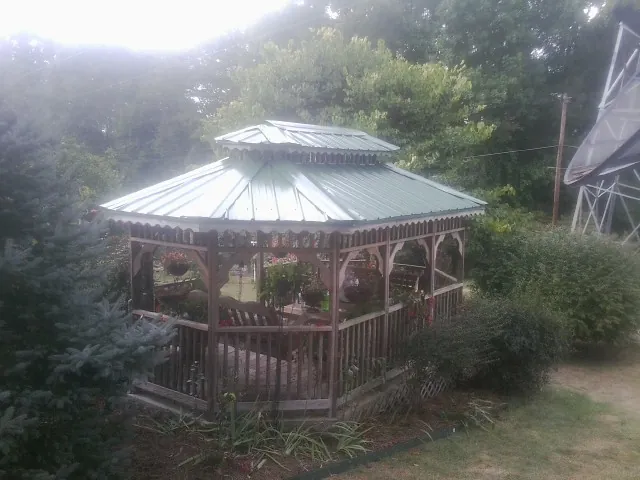 Green metal roof on a backyard gazebo surrounded by garden beds in Fallston