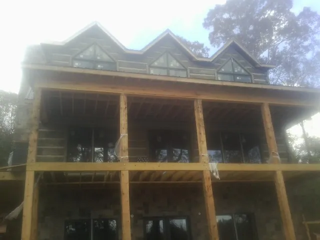 Dormers and porch framing on a large log home under construction — Roof Coating work by our crew in Fallston