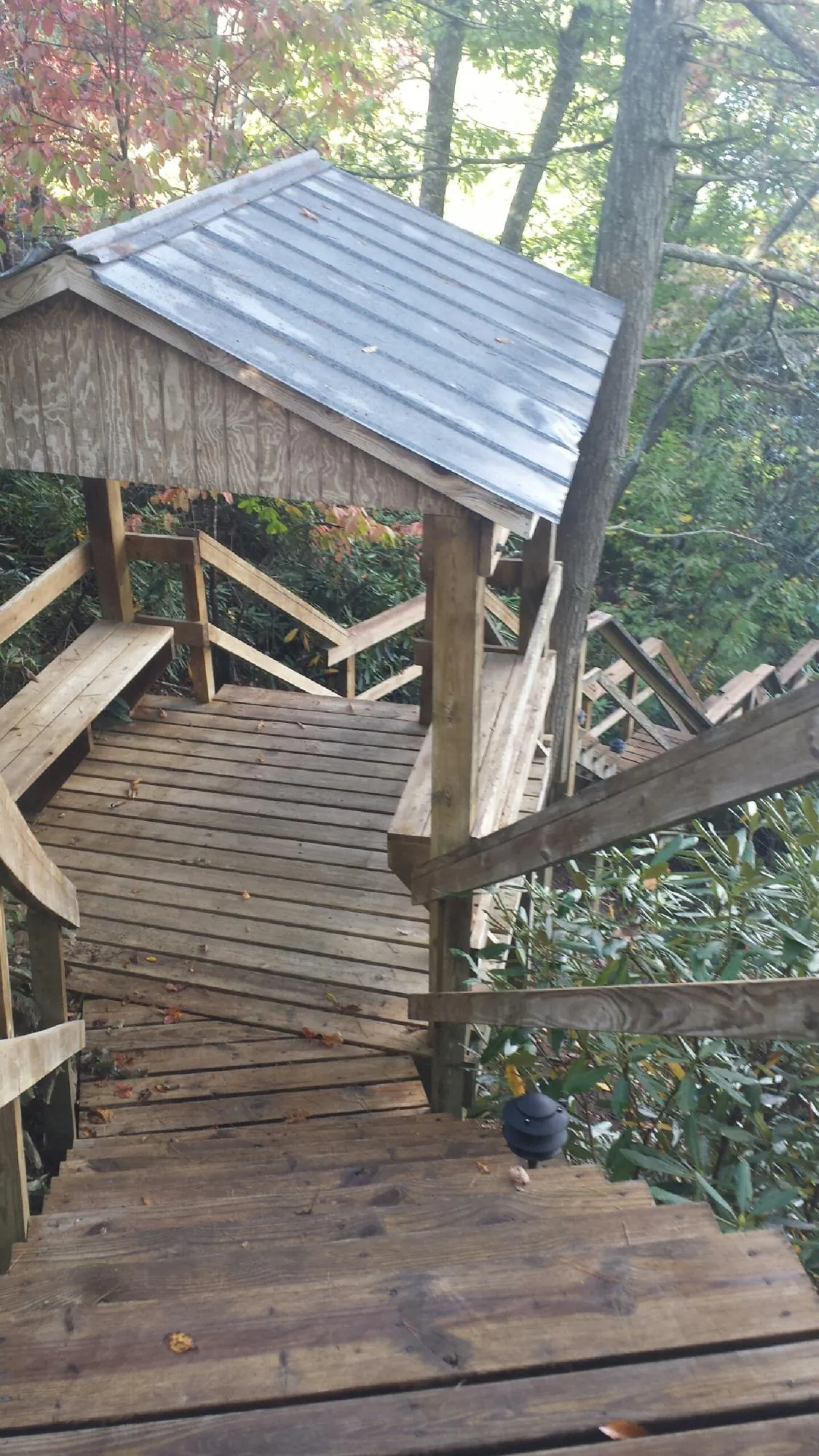Metal roofed shelter over wooden steps on a wooded walkway — Skylight Repair & Installation work by our crew in Fallston