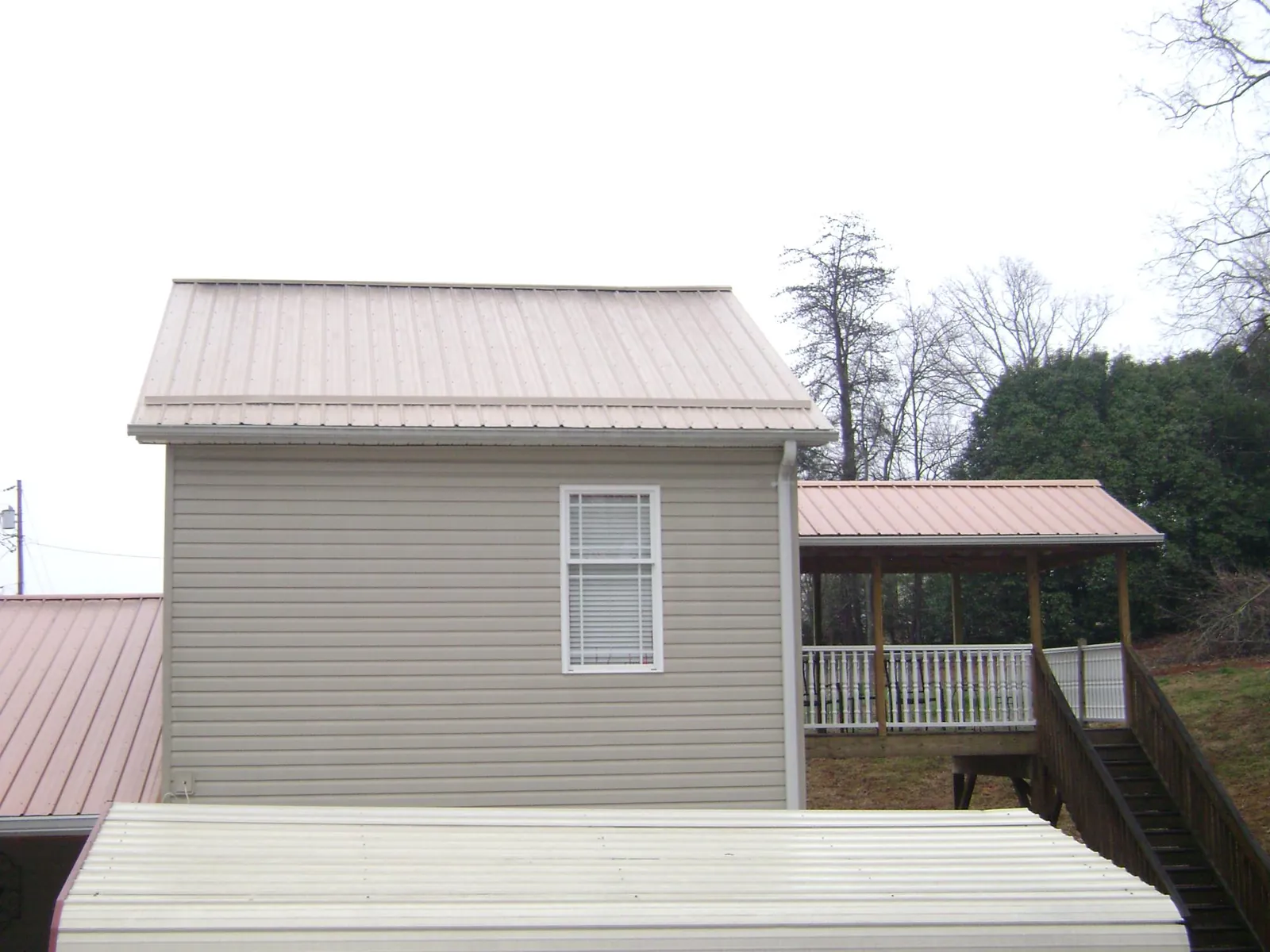 Tan metal roofs on a two story addition and attached porch, from a Roof Replacement job in Fallston